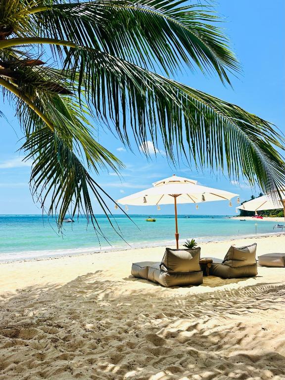 ein Strand mit Liegestühlen und einem Sonnenschirm und das Meer in der Unterkunft SOLEA Beach in Nathon Bay