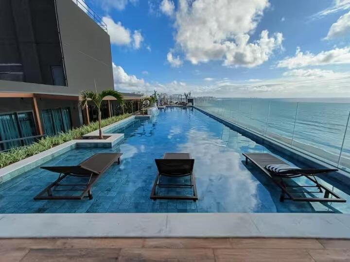 a swimming pool with chairs and the ocean at Art Studio Mare Loft in Salvador