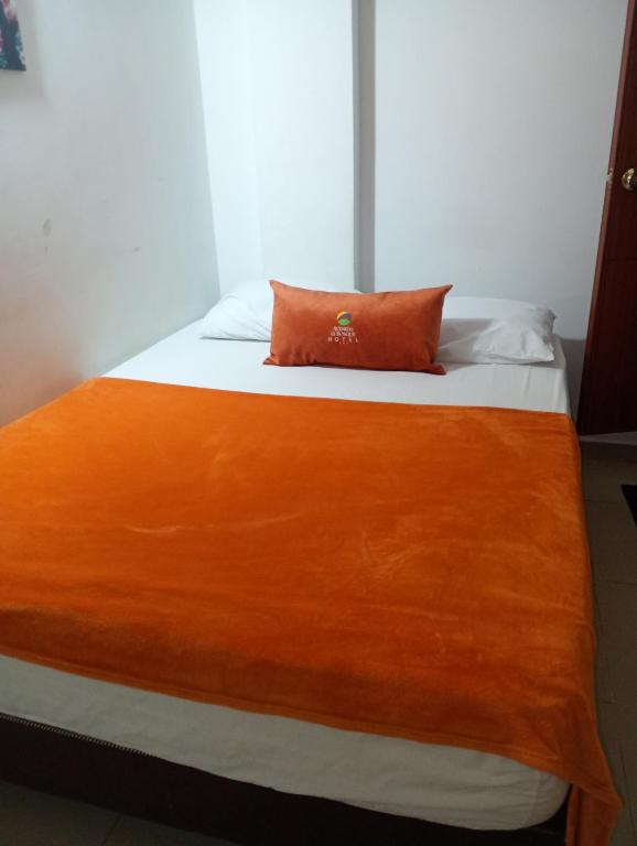 a bed with an orange pillow on top of it at Hotel Avenida El Bosque a 2 cuadras de la clínica foscal y cardiovascular,HIC,Unab in Floridablanca