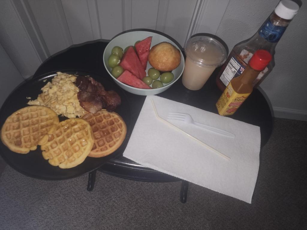 a plate of food with waffles and a bowl of fruit at Saffire Villa Rooms in Tacoma