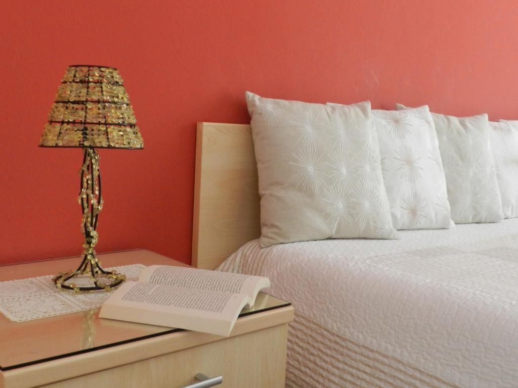 una cama con una mesa con una lámpara y un libro en Actinia Accommodation, en Alghero