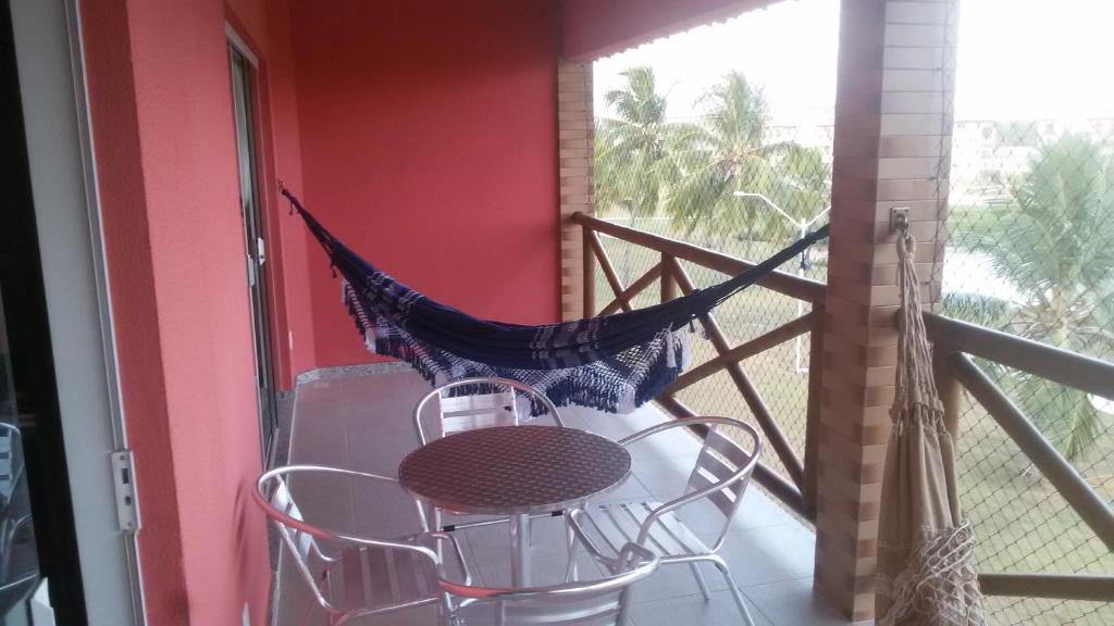 un balcón con hamaca, mesa y sillas en Apart Resort Villa das Águas, en Praia do Saco