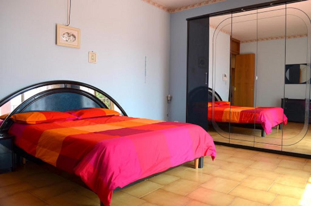 1 dormitorio con cama y espejo grande en B&B Le Tre Rose Di Maria, en Pedara