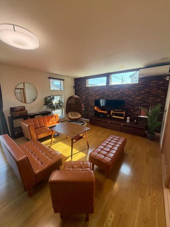 a living room with leather furniture and a brick wall at 函館 FabulousHouse 一棟貸し最大17名 in Hakodate