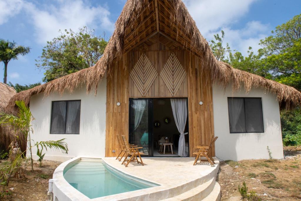 a house with a thatched roof and a swimming pool at Corales de Isla Fuerte in Puerto Limón