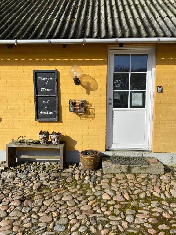 a yellow building with a white door and a sign at Ellemose Bed and Breakfast in Lemvig