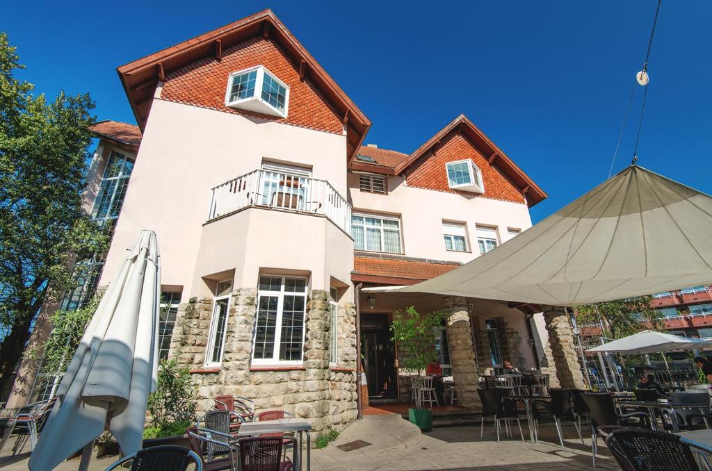 a building with an umbrella and tables and chairs at Hotel Harrison Etxea in Amorebieta-Etxano