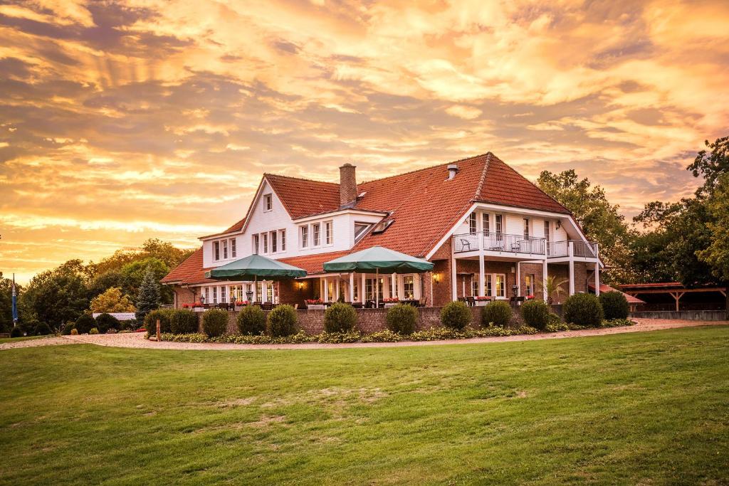 une grande maison blanche avec une pelouse verte dans l'établissement Hotel Reindahls, à Wilkendorf