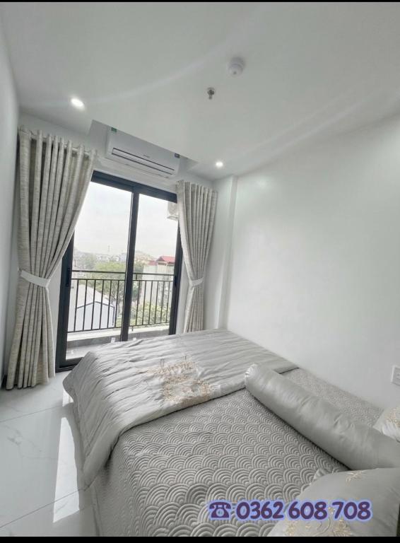 a bedroom with a bed and a large window at Rochomes Apartment in Thịnh Châu