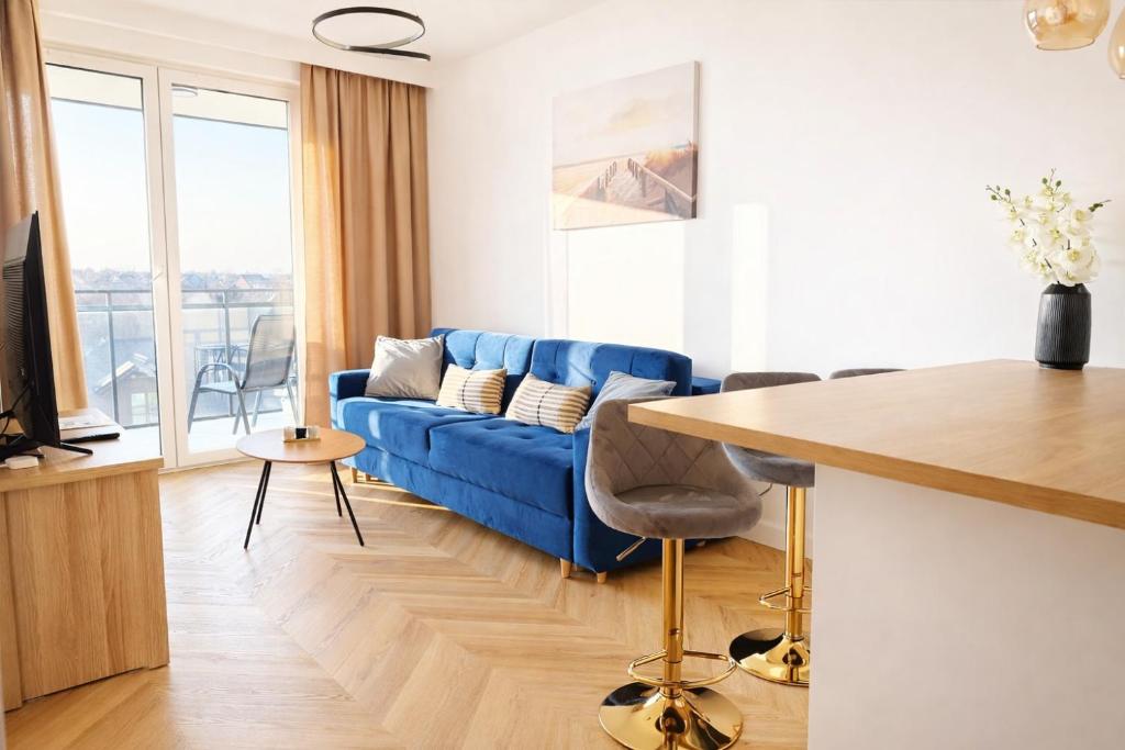a living room with a blue couch and a table at Jarzebinowa Loft III by JumpInHere in Nowy Dwór Mazowiecki