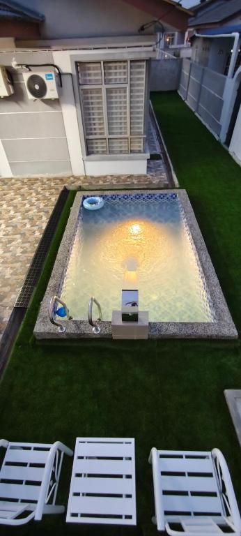 a swimming pool with two lawn chairs and a table and two chairs at FS Homestay Cherating in Kuantan