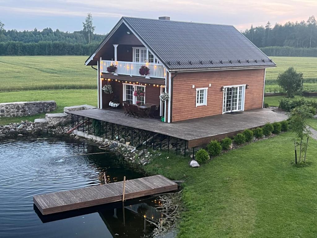 a house on a dock next to a body of water at Cozy Sauna House at Sinso Talu in Ülejõe