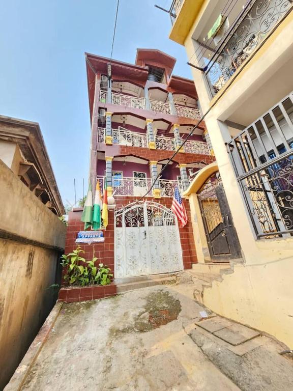 a red brick building with a white gate and a flag at FOKOU House in Yaoundé