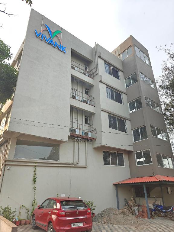 a red car parked in front of a building at Hotel Vivank in Kolhapur