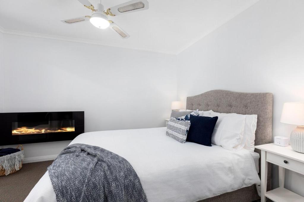 a white bedroom with a bed and a fireplace at Charming CBD cottage - walk everywhere in Mount Gambier