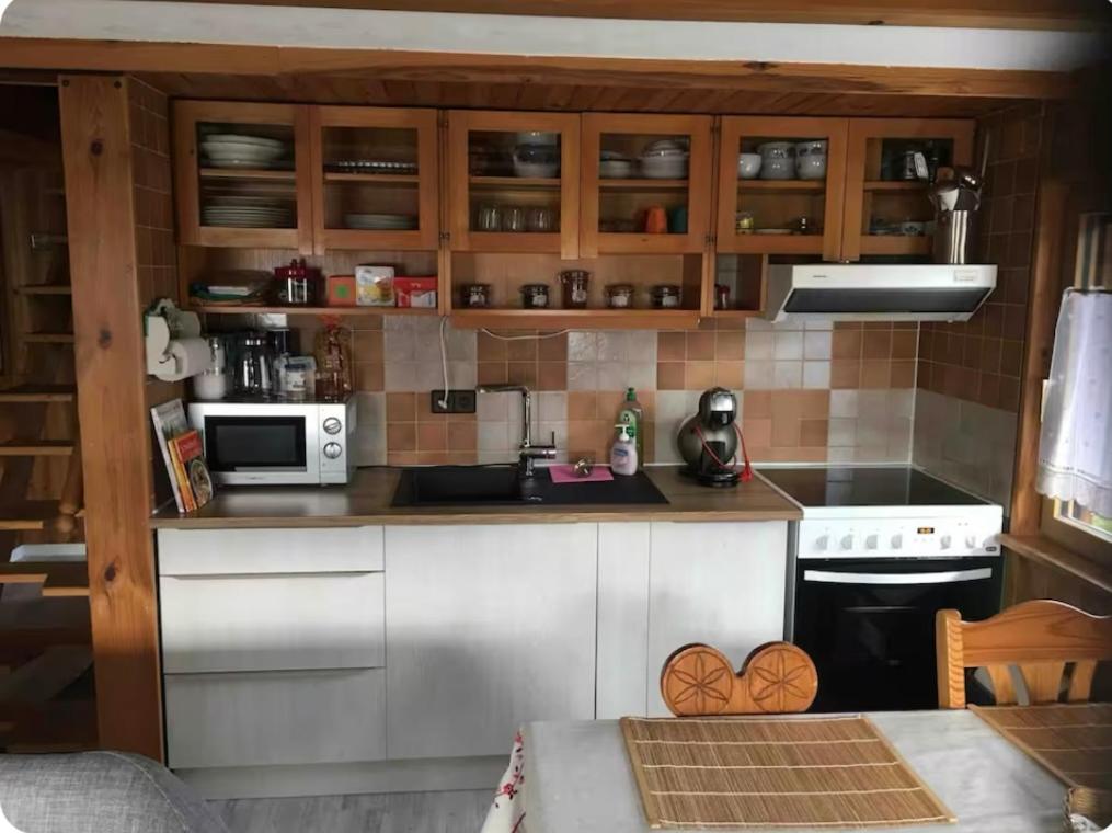 a small kitchen with white cabinets and a stove at Gîte le Nid in Langatte