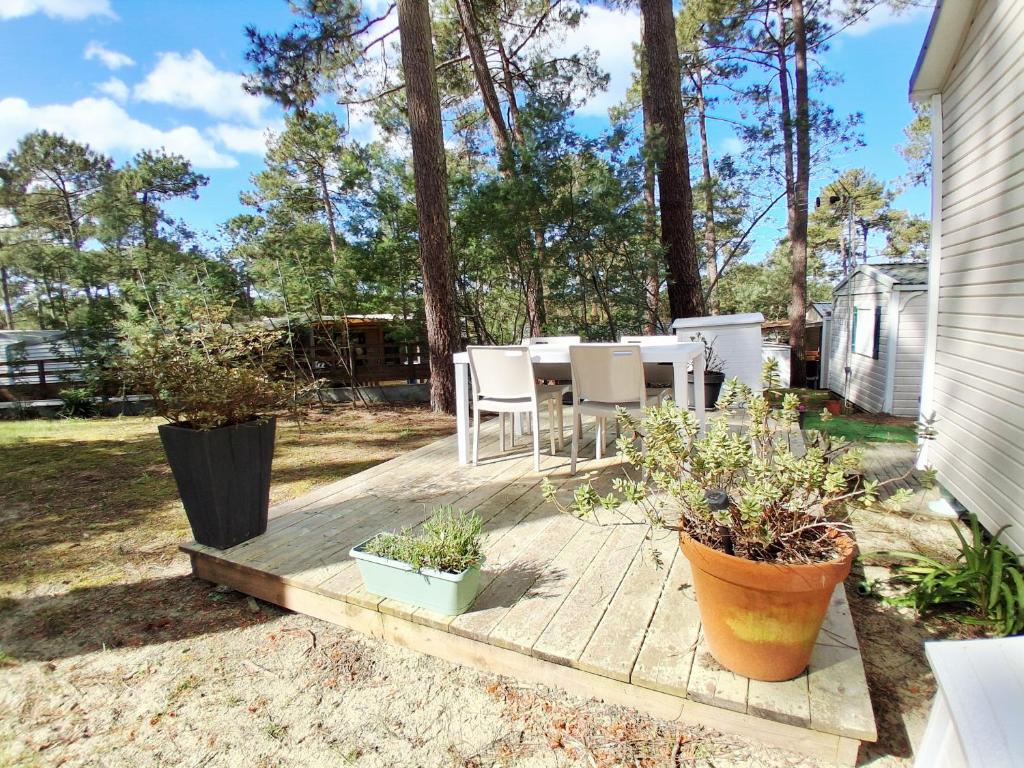 a patio with a table and chairs and some plants at CAMPING Les EMBRUNS - 4 ETOILES in Lège-Cap-Ferret