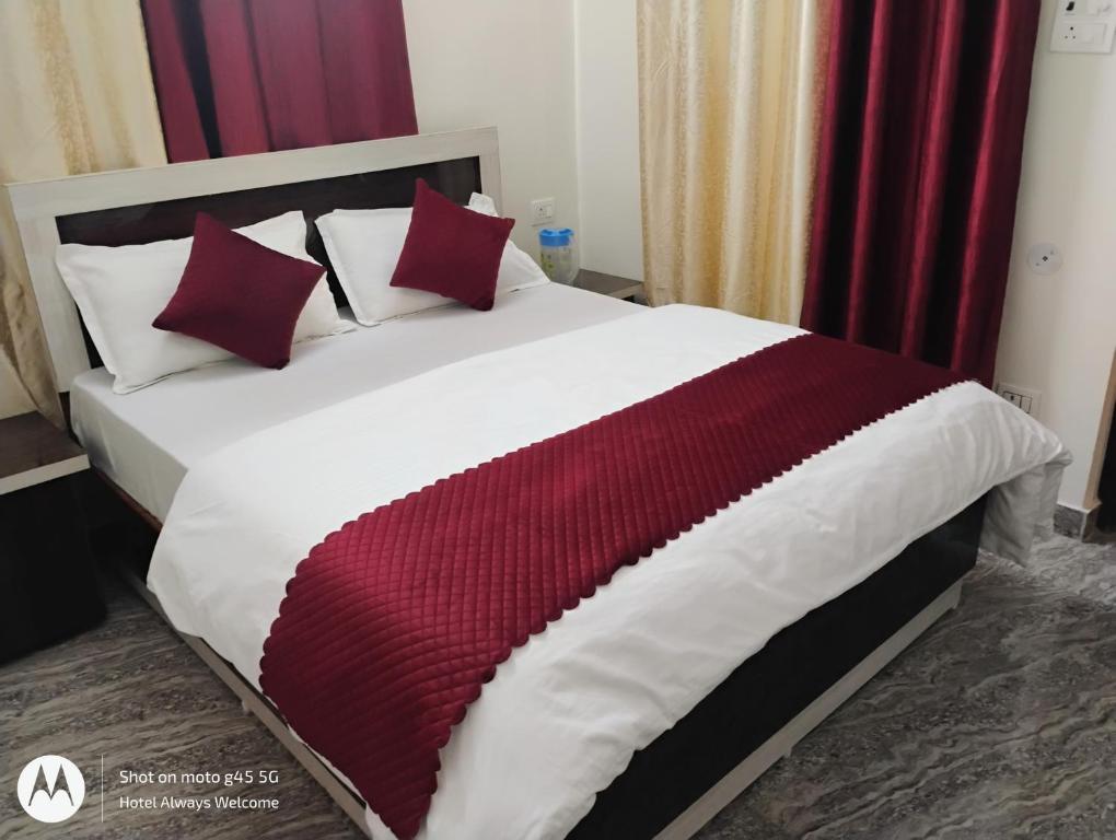a large bed with red and white blankets and pillows at Hotel Always Welcome in Nākuri