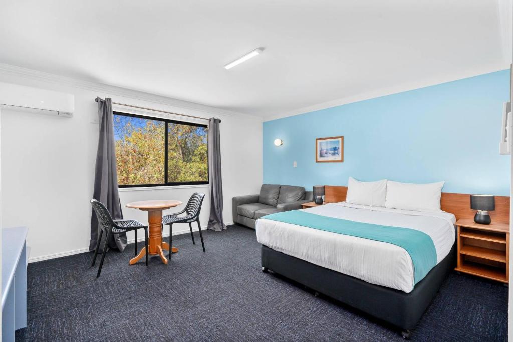 a hotel room with a bed and a couch and a table at Econo Lodge Waterford in Loganlea