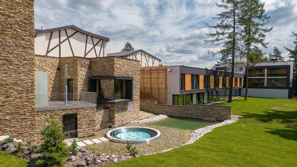 a large brick house with a swimming pool in the yard at Hotel Hills in Tatranská Lomnica