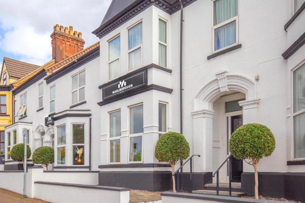 a white house with a black sign on it at Marlborough Hotel in Norwich