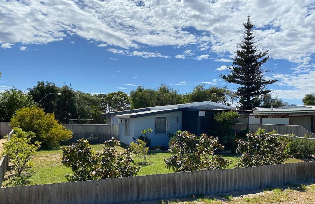 a blue house in a yard with a fence at Blue Marlin, 12 Westlake Way in Jurien Bay