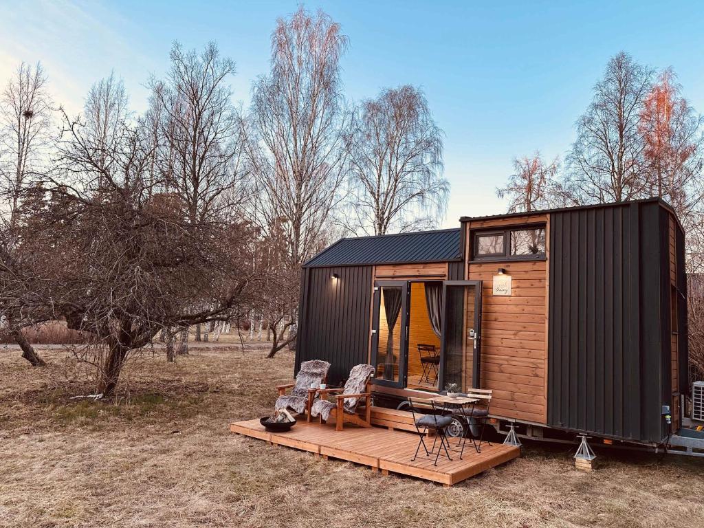 a tiny house with a deck and two chairs at Stockholm Archipelago by Tiny Away in Fagerdala