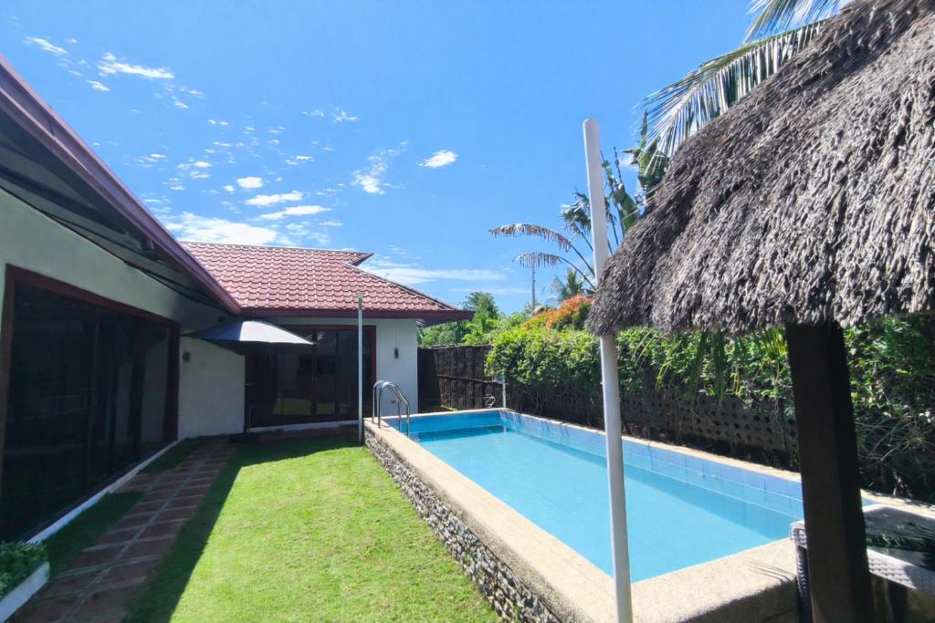 a swimming pool next to a house with an umbrella at Villas Flora Bella Sunflower in Dauis