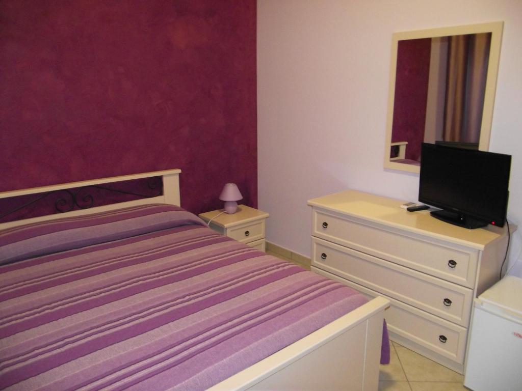 ein Schlafzimmer mit einem Bett und einer Kommode mit einem TV in der Unterkunft Il Glicine in Capo dʼOrlando