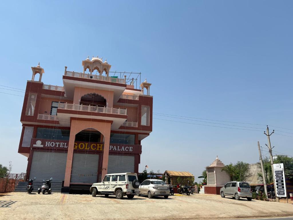 a building with cars parked in front of it at Hotel Golchi Palace in Lālsot