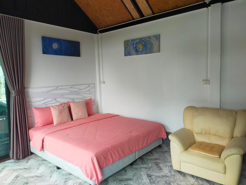 a bedroom with a pink bed and a chair at Good View Guest House in Phatthalung