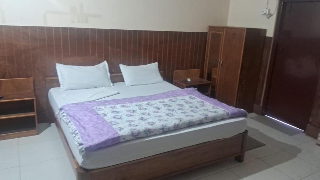 a bedroom with a large bed with a wooden headboard at Hotel Silver Dragon, NK Darranga in Darranga