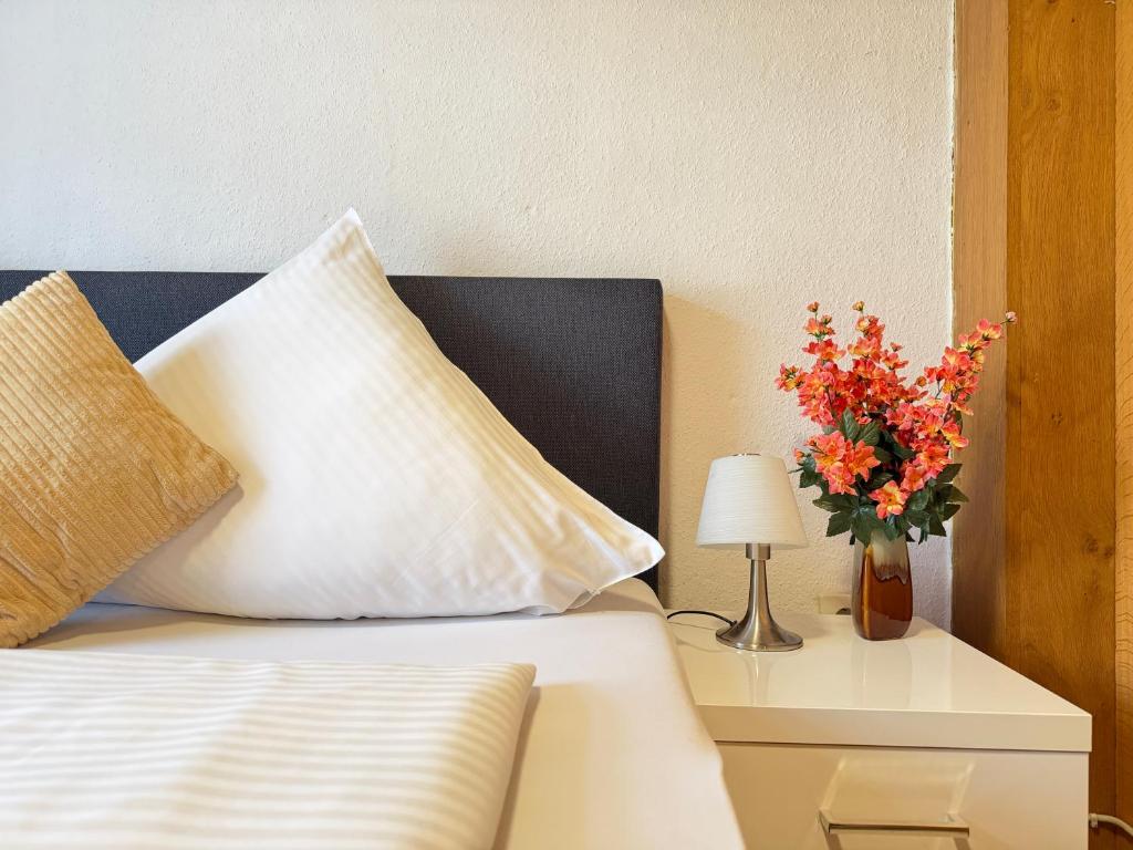 a bed with a pillow and a vase of flowers on a table at Asia Oase in Arendsee