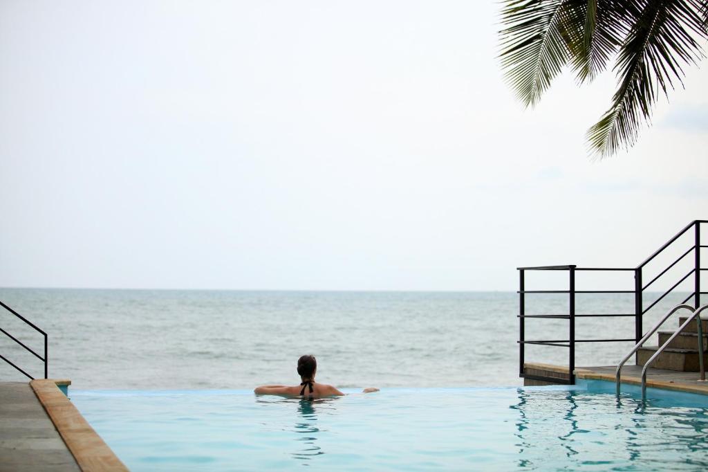 a man in a swimming pool looking out at the ocean at 36 Palms Boutique Retreat in Cherai Beach