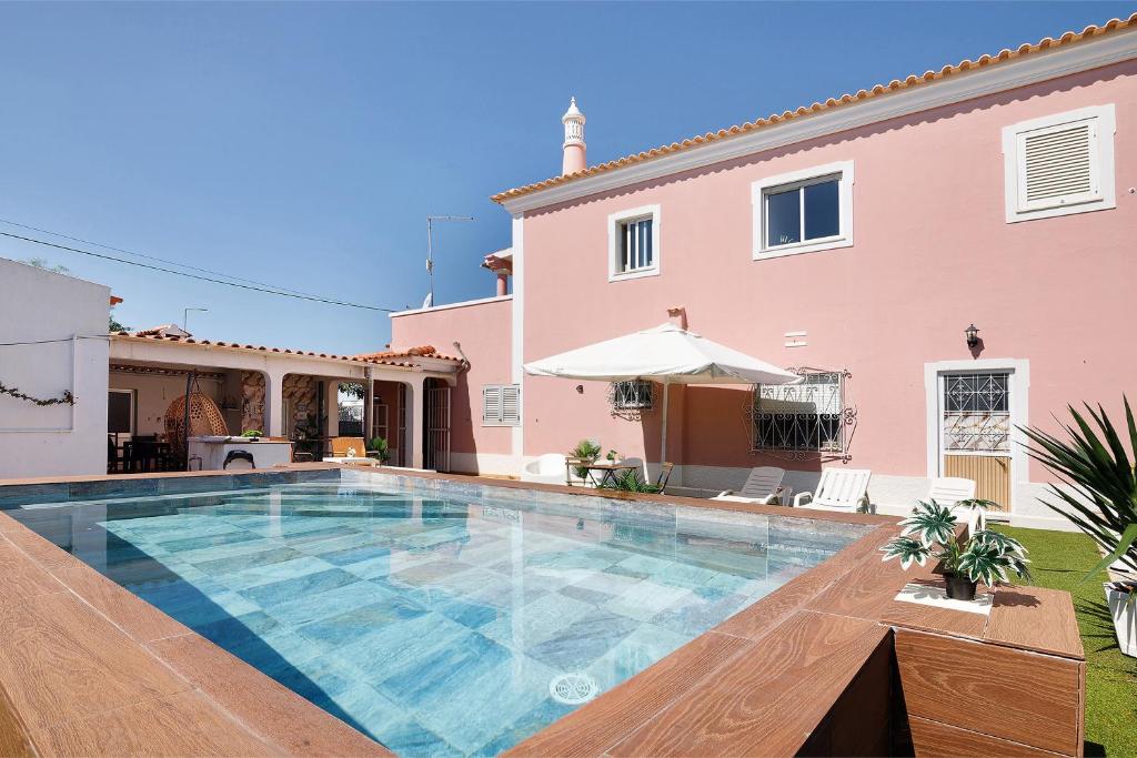 a swimming pool in front of a house at J R Dream house in Quarteira