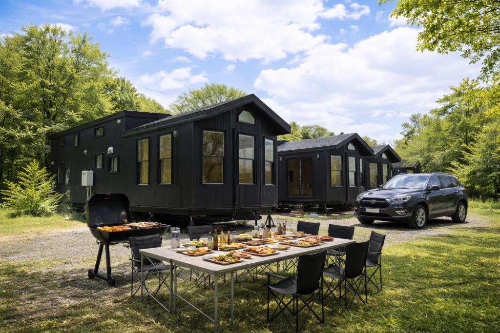 a black tiny house with a table and chairs at ペンションハートウォーマー in Myoko