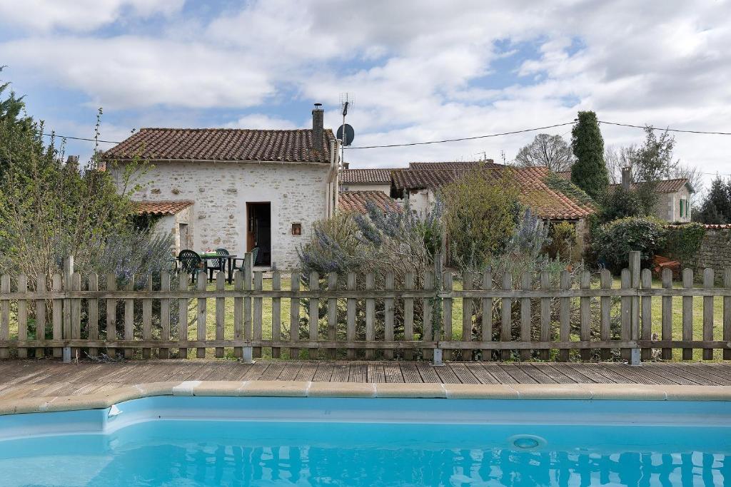 a house behind a wooden fence with a pool at Gîte des Fraignaies in Saint-Juire-Champgillon
