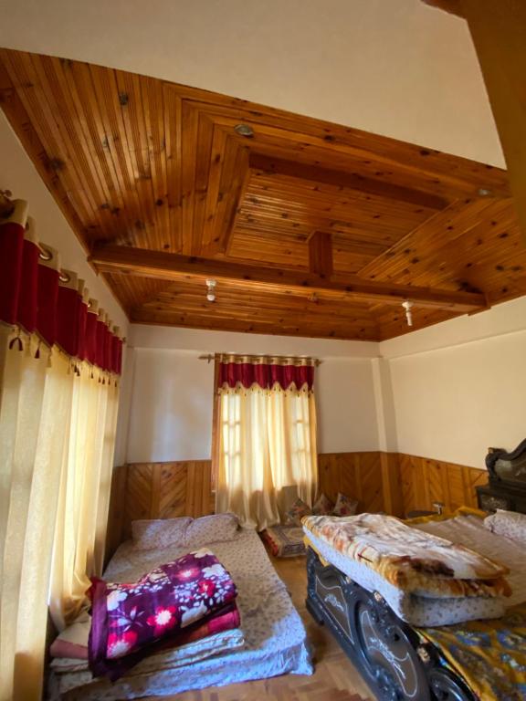 a bedroom with two beds and a wooden ceiling at Walking Trails homestay in Baragrān