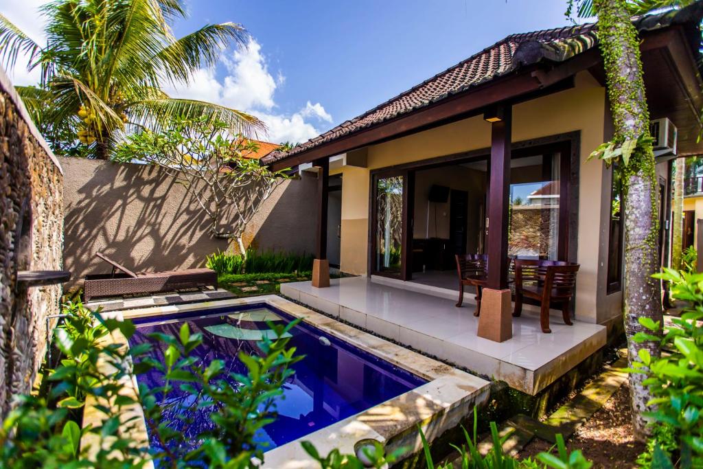a villa with a swimming pool in front of a house at Villa Mandi Resort & spa in Ubud