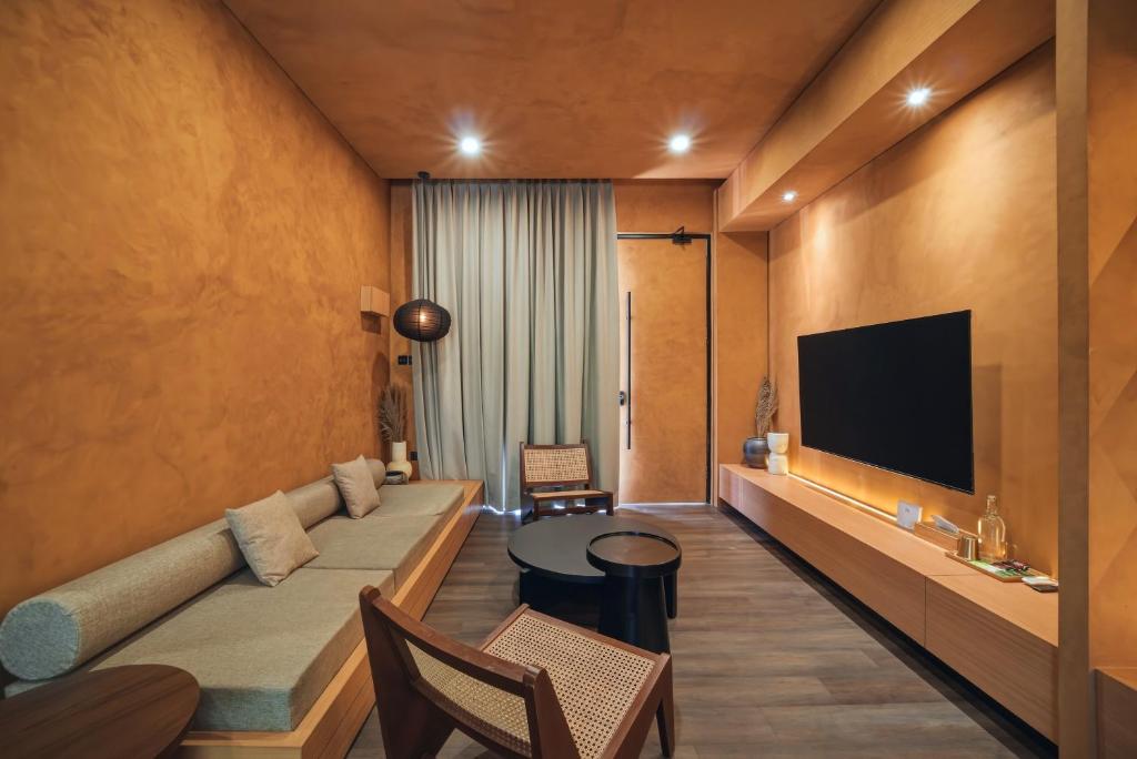 a hotel room with a couch and a flat screen tv at Redbrick Villa By The Feelas in Bandung
