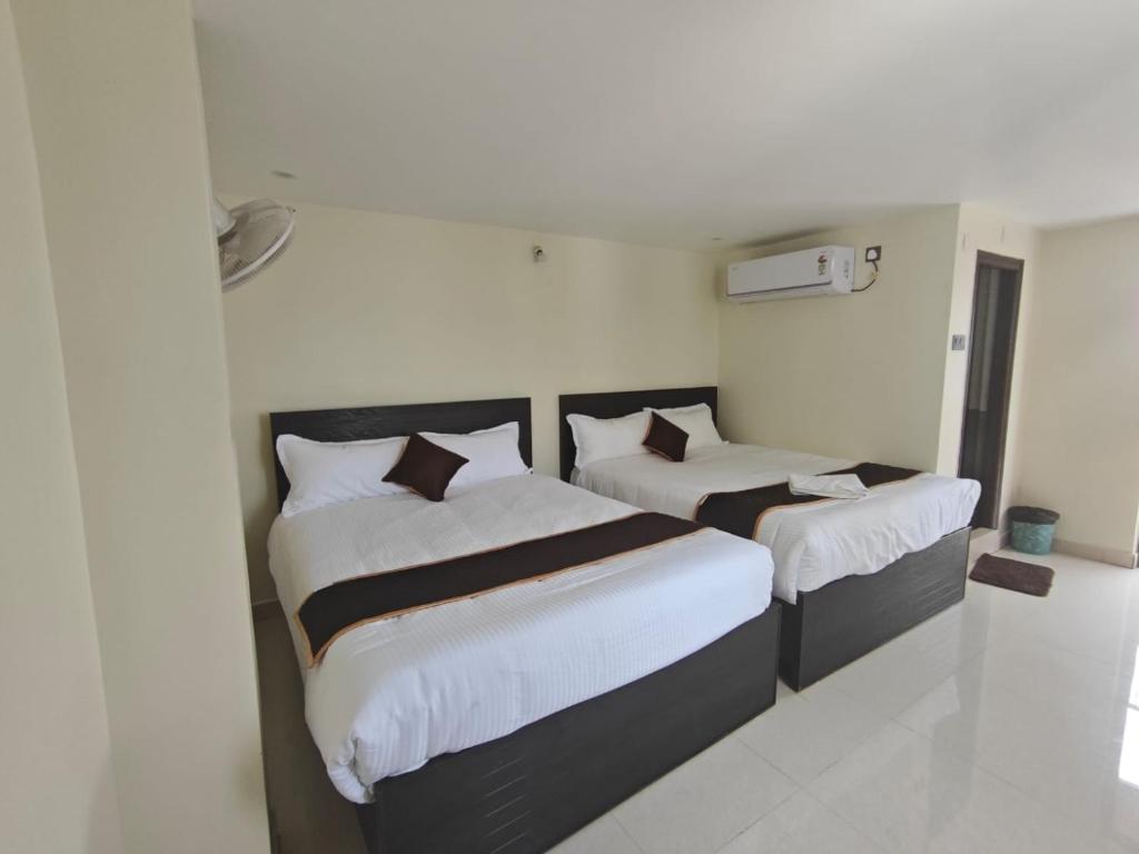 two beds in a hotel room with white walls at HOTEL VAJRA Grand in Tirupati