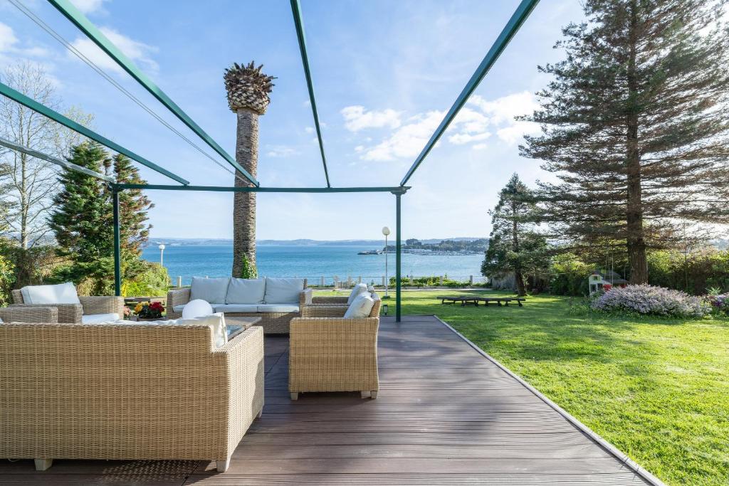 a patio with a view of the ocean and a palm tree at El Chiripero Beach Villa in A Coruña