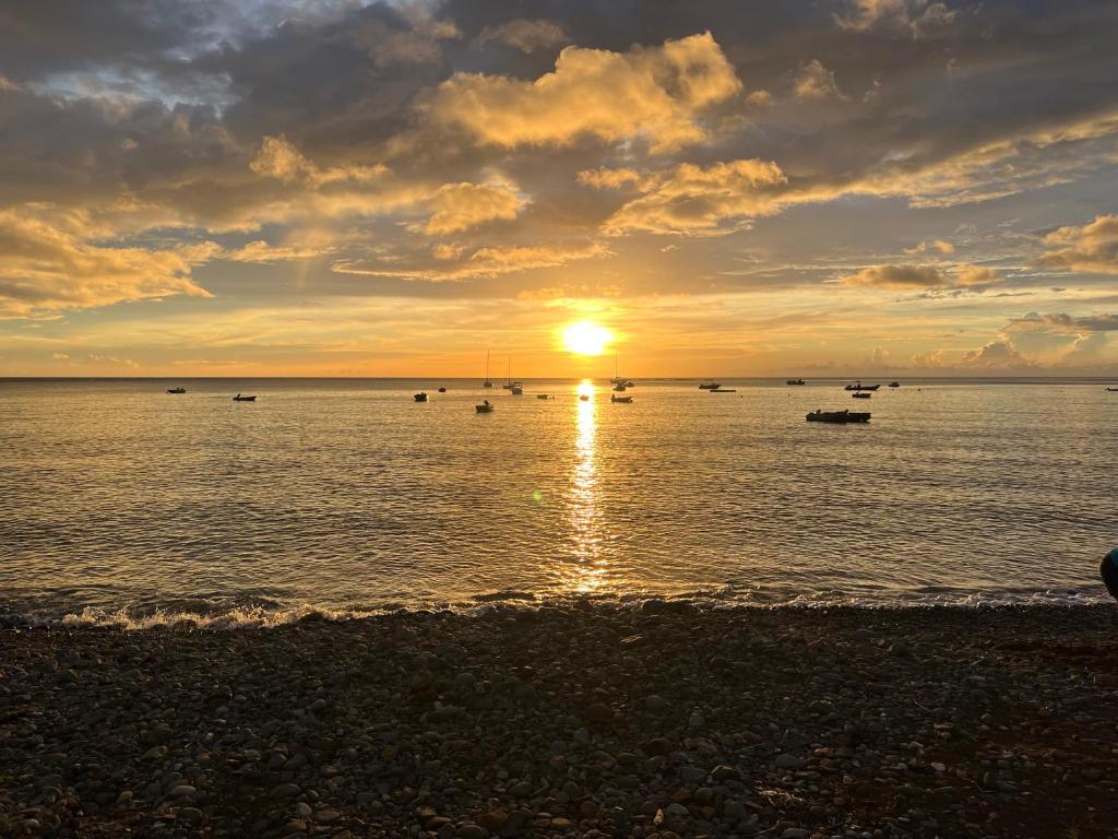a sunset over a body of water with boats at Séjour Caraïbe in Pointe-Noire