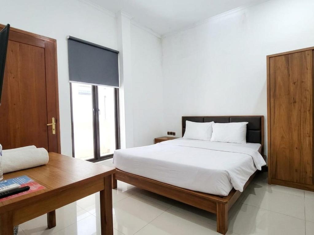 a bedroom with a white bed and a wooden desk at Casa Palma by Ezzego in Bandung