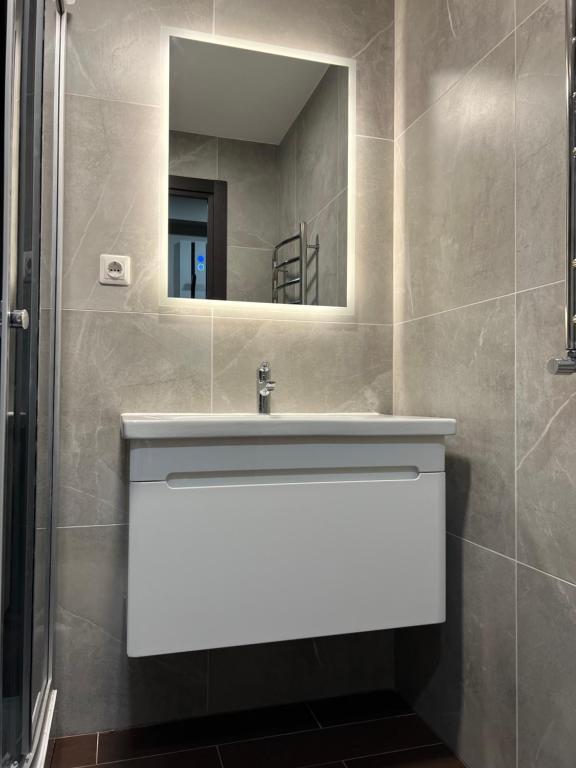 a bathroom with a white sink and a mirror at Ludza Comfort Apartment in Ludza