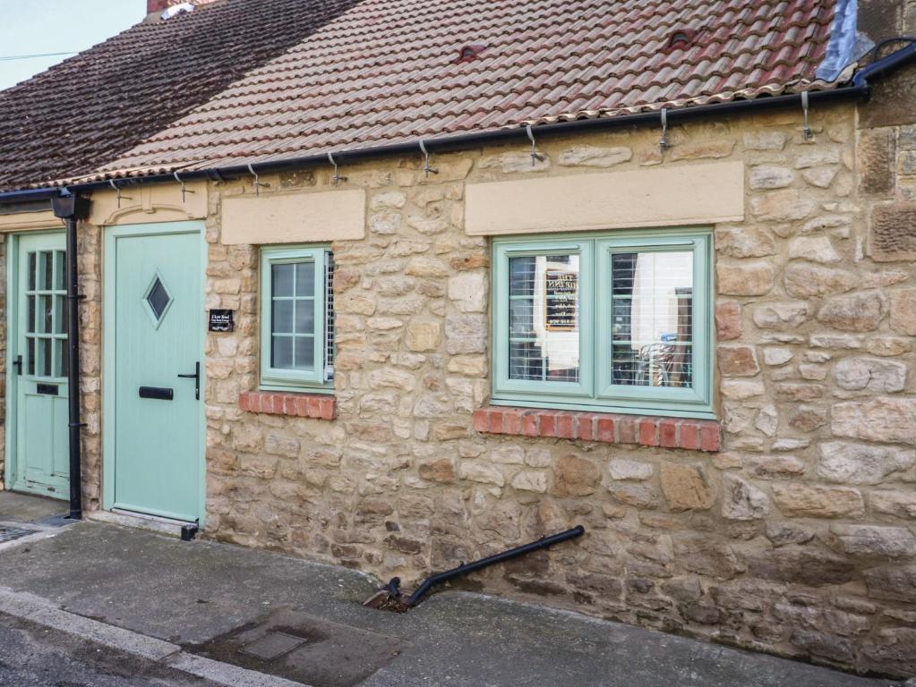 a stone house with two windows and a blue door at 2 Low Road in Bishop Auckland
