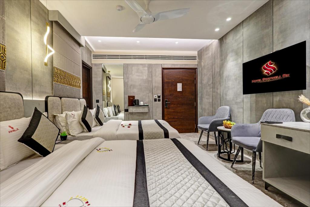 a hotel room with two beds and a table and chairs at Hotel Stay Well Dx in New Delhi