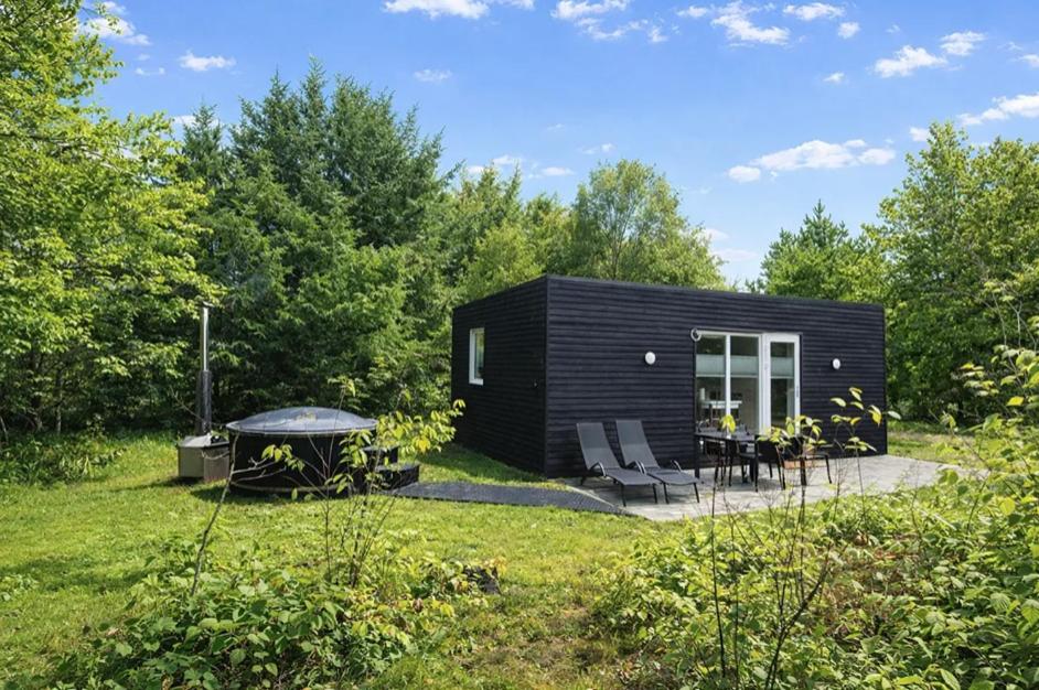 a black tiny house in the middle of a yard at Rødhus Camping in Pandrup