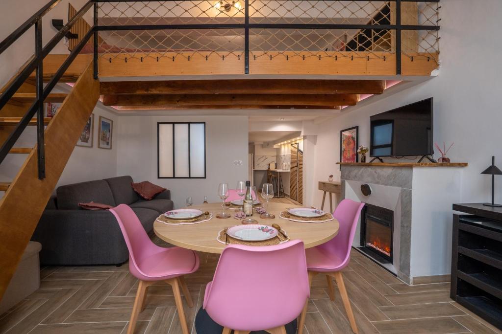 a dining room and living room with a table and pink chairs at La vie en rose in Grasse