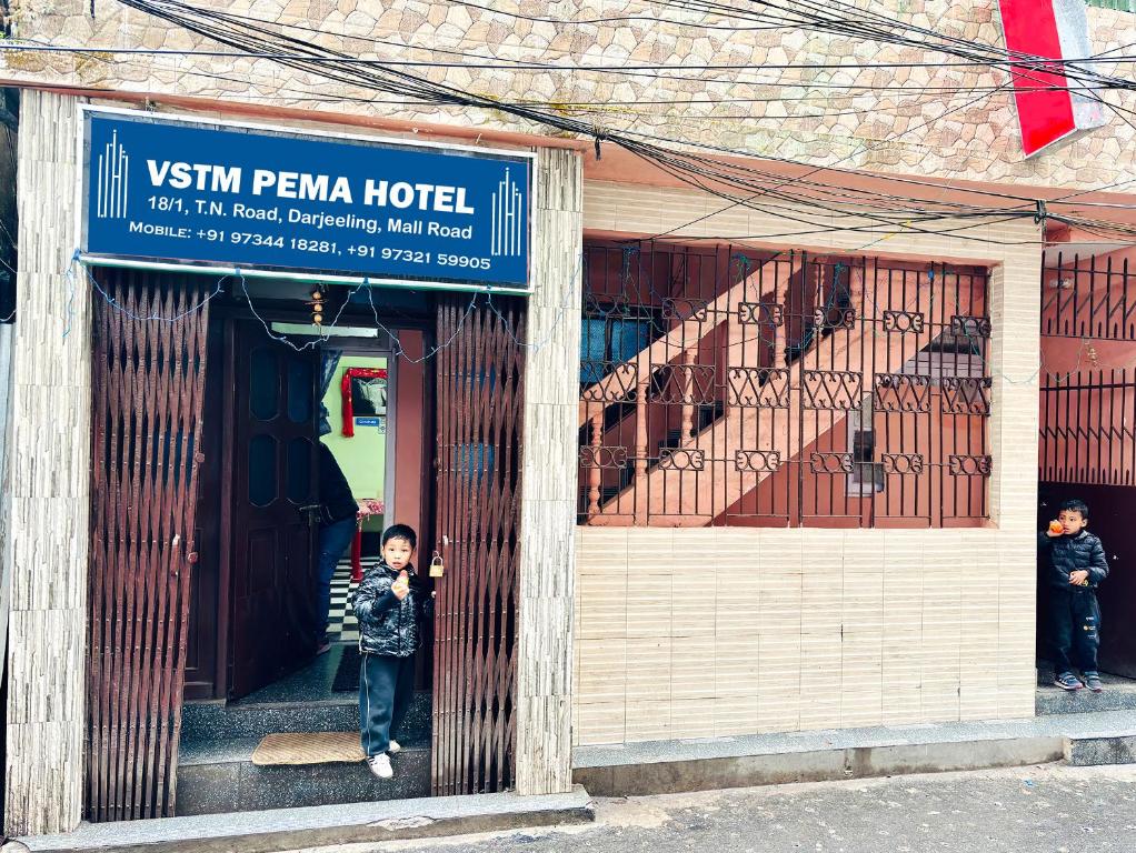 a young boy standing in the doorway of a building at PEMA Hotel VSTM in Darjeeling
